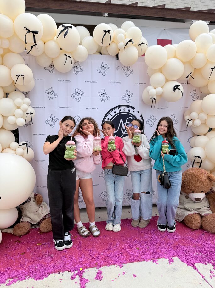 Young guests posing at the Nails of America Fulshear photo booth with bear-themed drinks